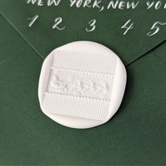 a white button sitting on top of a green envelope with the word new york written in it