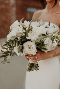 a woman holding a bouquet of white flowers