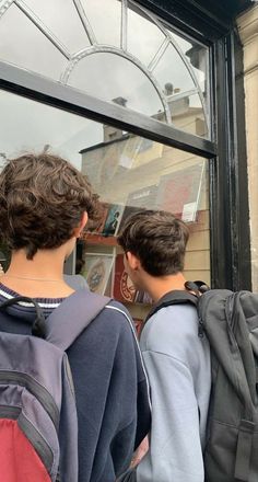 two young boys are looking out the window at something in front of them that is on display