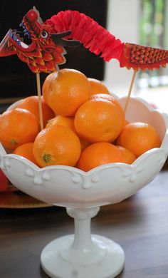 a bowl filled with oranges on top of a wooden table