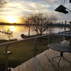 the sun is setting over a lake and some trees