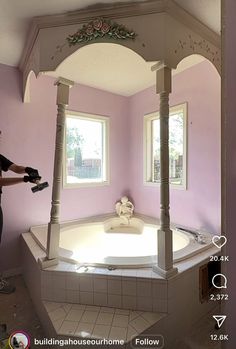 a woman is painting the inside of a bathroom with pink walls and white trimming