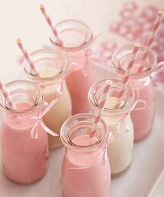 four mason jars filled with pink liquid and straws on a white plate next to two cups