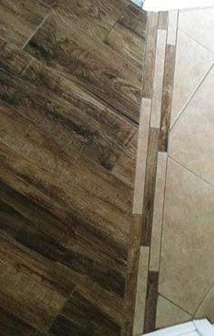 a toilet sitting next to a wooden floor on top of a tiled floor in a bathroom