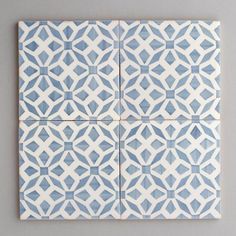 four blue and white tiles are arranged in the shape of an intricate pattern on a wall