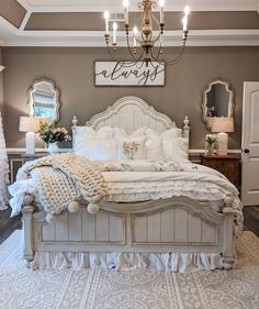 a large white bed sitting in a bedroom next to a chandelier and window