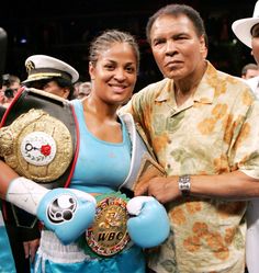 a man and woman standing next to each other in front of a crowd with boxing gloves on