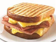 a grilled cheese sandwich with bacon and melted cheese on toasted bread, sitting on a white plate