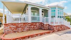 a mobile home is shown with brick and white railings on the front porch, along with a car parked in the driveway