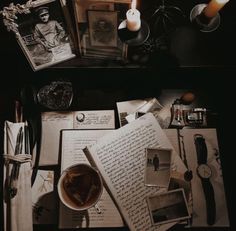 an assortment of books and other items on a table with candles, pictures, and photos