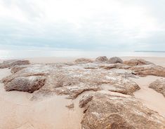 rocks and sand on the beach under a cloudy sky