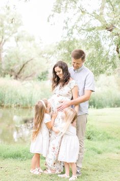 a family standing in front of a pond during their outdoor photo session at the park