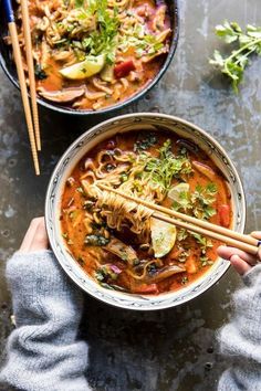 two bowls of soup with chopsticks on the side and another bowl full of noodles