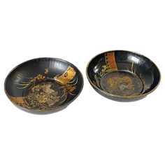 two black and gold bowls with designs on them