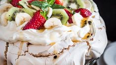 there is a cake with fruit on top and whipped cream around the edges, topped with kiwis