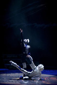 two dancers performing on stage in the dark