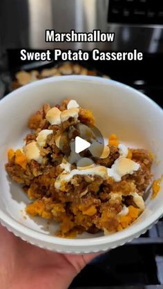 a person holding a bowl of food in their hand with the words marshmallow sweet potato casserole