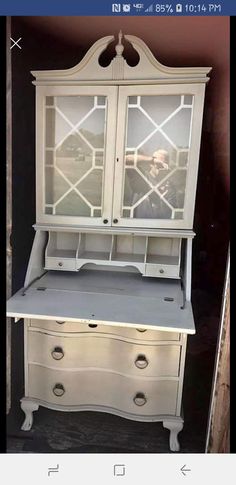 a white dresser with glass doors and drawers