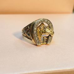 a gold ring with a horse head on it sitting on top of a white surface