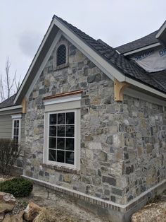 a stone house with white trim and windows