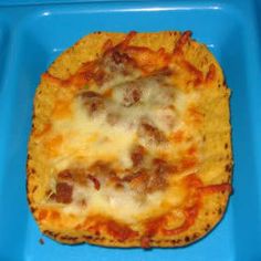 a square shaped pizza sitting on top of a blue plastic tray with cheese and meat toppings