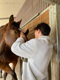 a man is petting a horse in an enclosed area