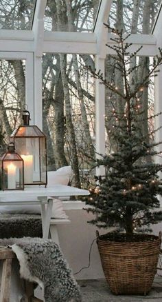 a small christmas tree in a basket next to a table with candles and lights on it