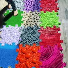 a person standing next to a colorful rug on top of a wooden floor in front of a child's feet