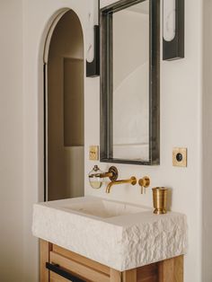 a bathroom sink sitting under a mirror next to a wall mounted faucet in front of a doorway