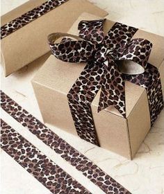 a brown box with a leopard print ribbon on it next to two rolls of tape