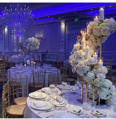 the tables are set with white flowers, candles and place settings for an elegant dinner