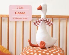 a stuffed duck sitting on top of a pillow next to a crib with the words goose