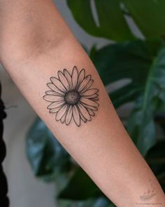 a woman's arm with a black and white flower tattoo on the left forearm