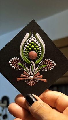 a hand holding up a black card with green and white designs on the front side