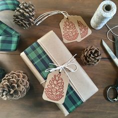 christmas presents wrapped in brown paper and tied with twine on wooden table next to pine cones