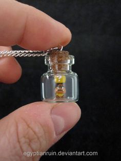 someone is holding a tiny glass bottle necklace