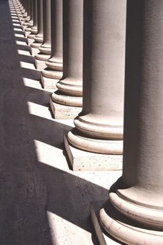 the columns are lined up and casting shadows on the concrete floor, with one person walking in the distance