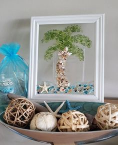 seashells and starfish are arranged on a tray in front of a framed tree