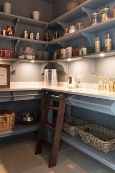 a kitchen with blue shelves filled with jars and other items on the counter top next to a ladder