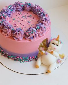 a pink cake with purple frosting and sprinkles