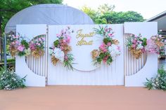 a white gate decorated with flowers and greenery