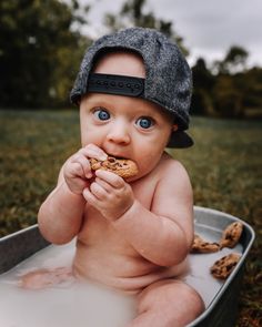 a baby is sitting in a tub with food and wearing a hat on his head