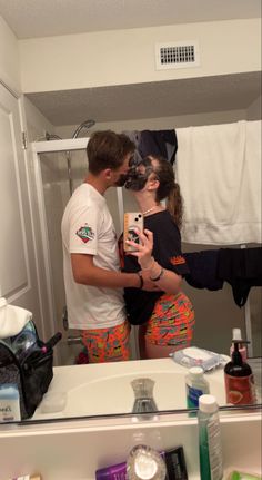 a man and woman standing in front of a bathroom mirror