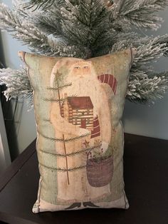 a decorative pillow sitting on top of a wooden table next to a christmas tree and potted plant