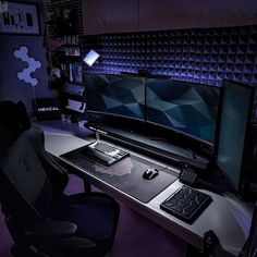 a computer desk with two monitors, keyboard and mouse on it in a dark room