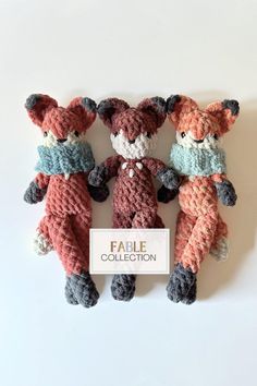 three crocheted teddy bears sitting next to each other on top of a white surface