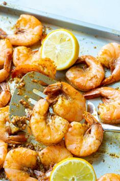 a pan filled with cooked shrimp and lemon wedges