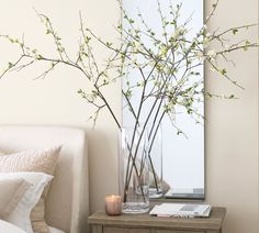 a bedroom with a bed, mirror and flowers in vases on the side table