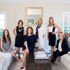 a group of women standing in a living room next to a couch and coffee table