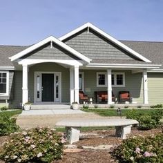 a house with a bench in front of it and bushes around the yard area on either side